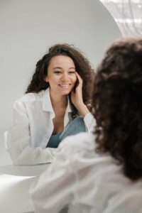 young woman pleased with herself in the mirror. Self esteem counseling in Houston, Tx is a great place to gain the tools and skills to truly love yourself. It can also help you to process all the things that have kept you stuck. 